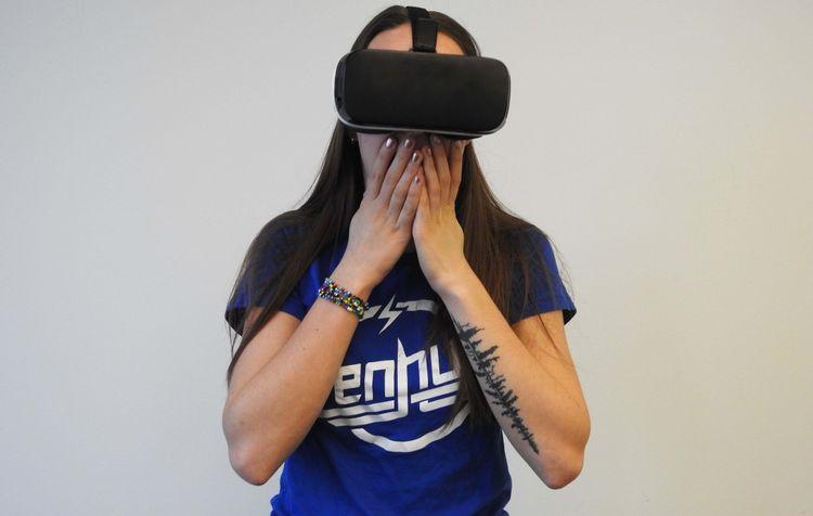 girl standing with virtual reality headset on with her hands over her mouth