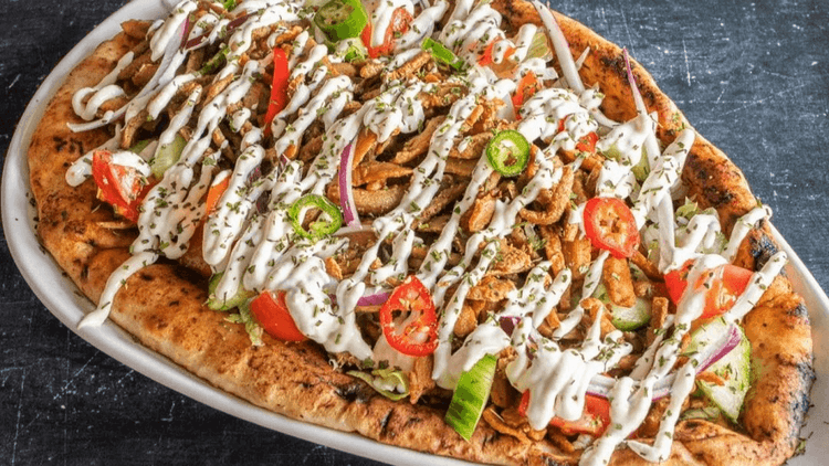 vegan kebab meat on a flatbread with white sauce and chillies